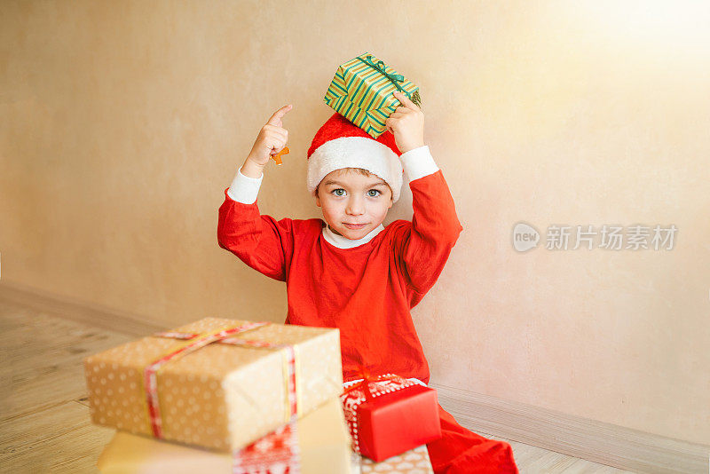4-5岁的小男孩穿着圣诞服装在家玩圣诞礼物。圣诞节庆祝活动的概念。