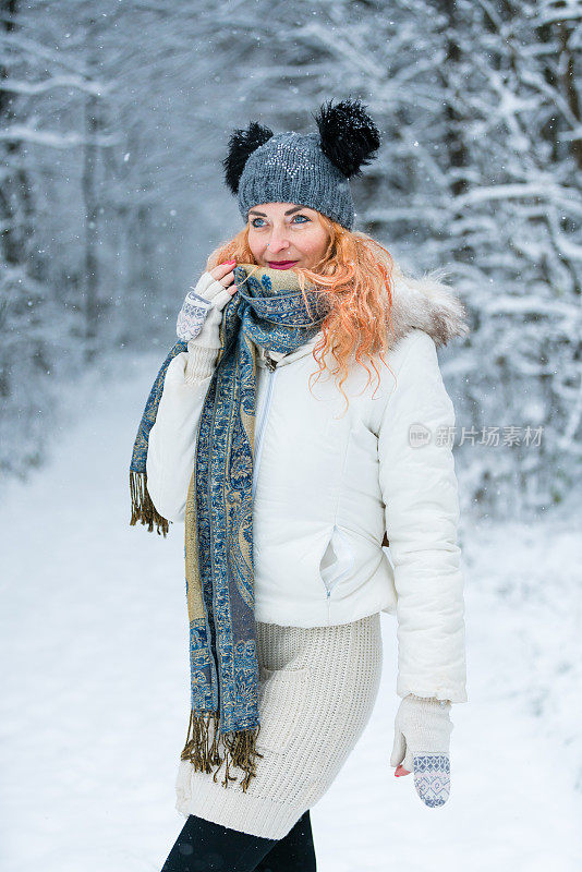 快乐的女人，在冬天森林附近的白雪皑皑的草地上