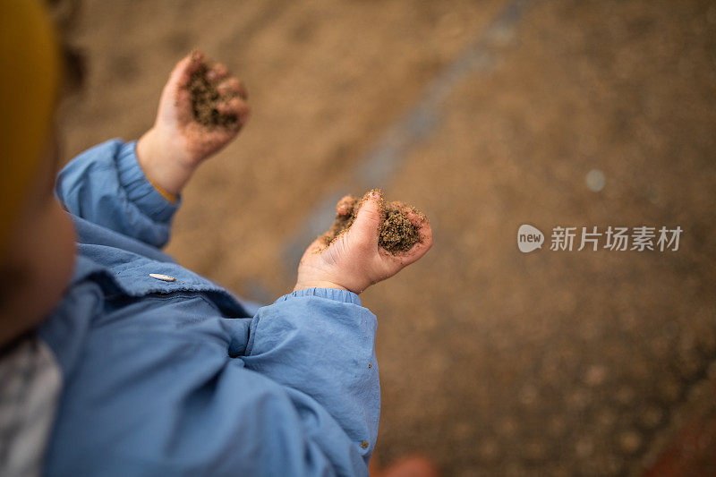 秋天的一天，顽皮的小男孩在操场上玩沙子