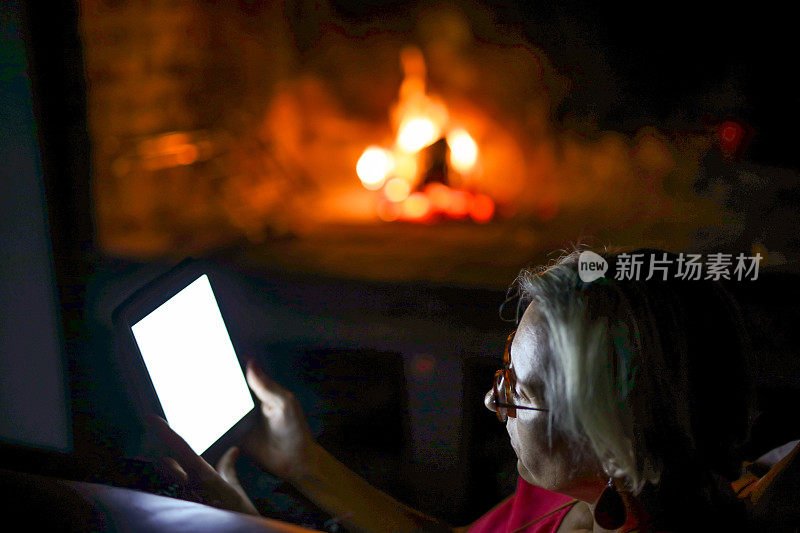 一位女士在壁炉旁看电子书