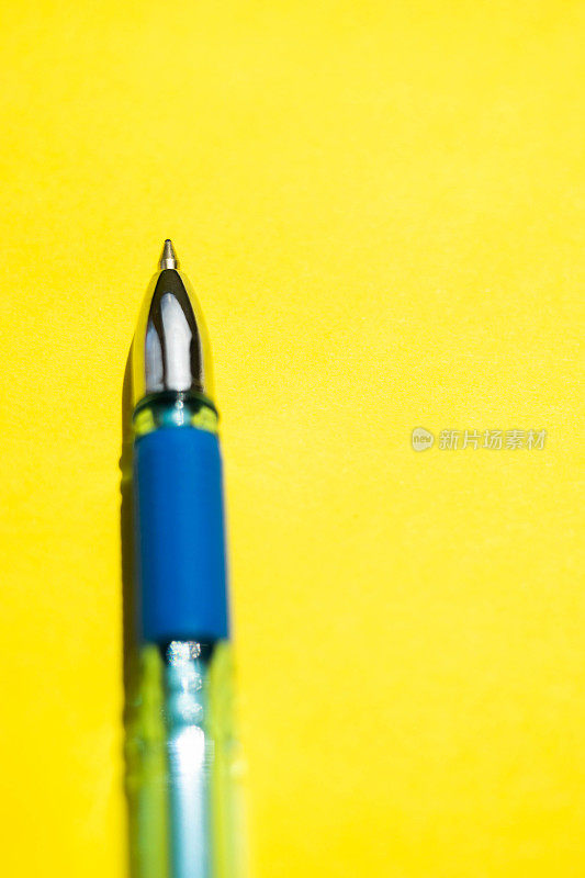 蓝色圆珠笔上明亮的阳光黄色纸的特写