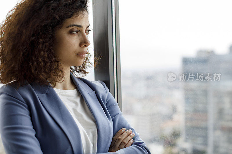 年轻体贴的女商人透过窗户往外看