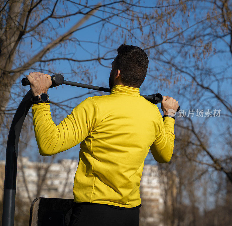 男人做引体向上运动后视，穿着黄色衬衫