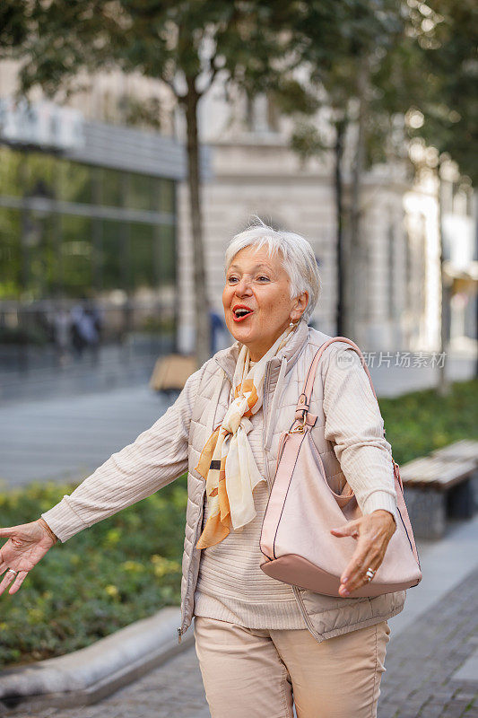 一位快乐的老妇人正走在街上，向购物中心走去。