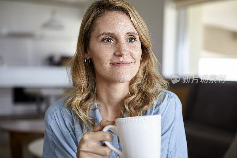 中年妇女的肖像拿着一杯咖啡，而看着别处的室内