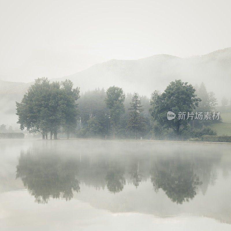 黎明时分湖面上的薄雾，树木和山脉