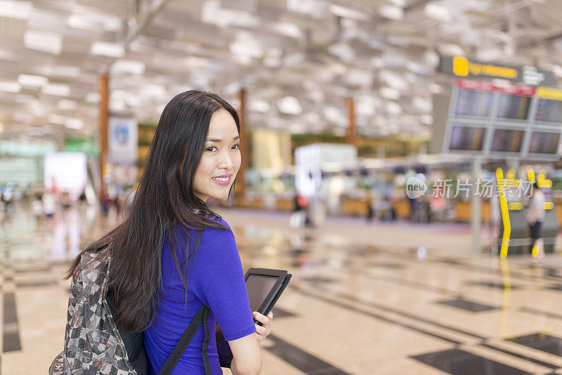 迷人的长发亚洲女人等候在机场候机厅