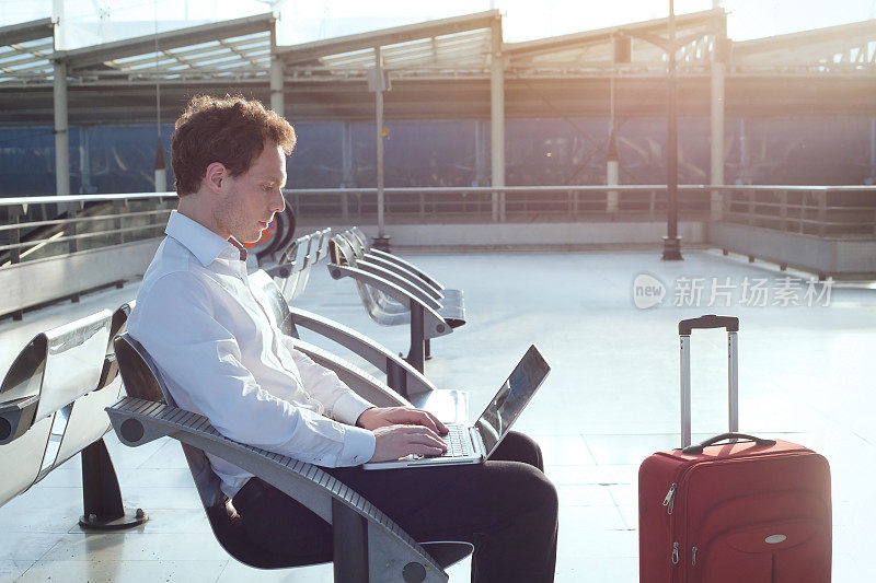 一个商人坐在机场拿着笔记本电脑