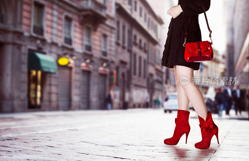 女孩穿着红色的包和红色的靴子在街上。