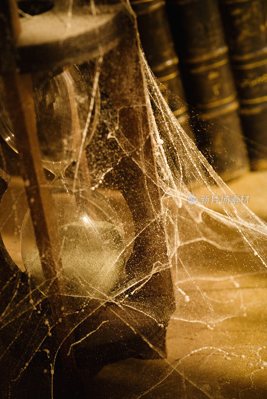 古书和布满蜘蛛网的沙漏