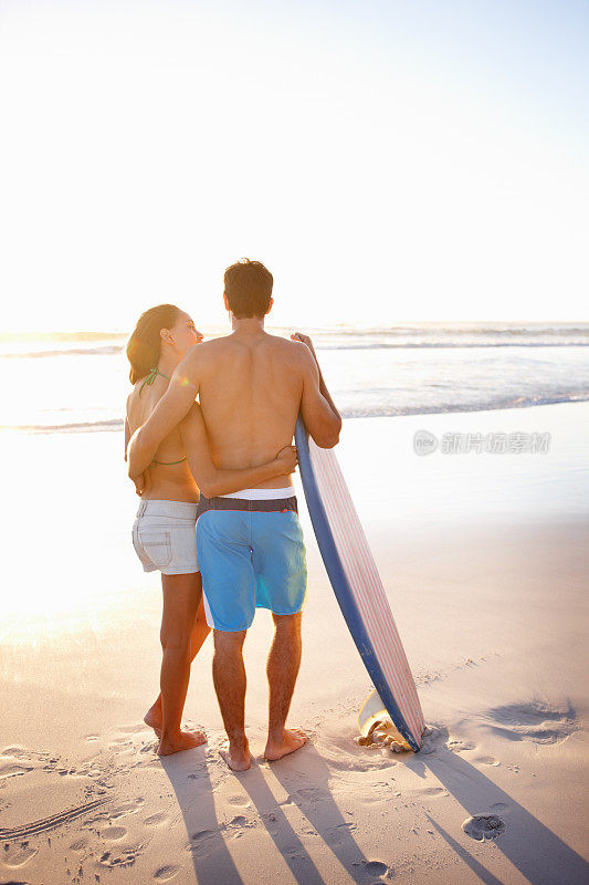 一对年轻夫妇在海边玩冲浪板