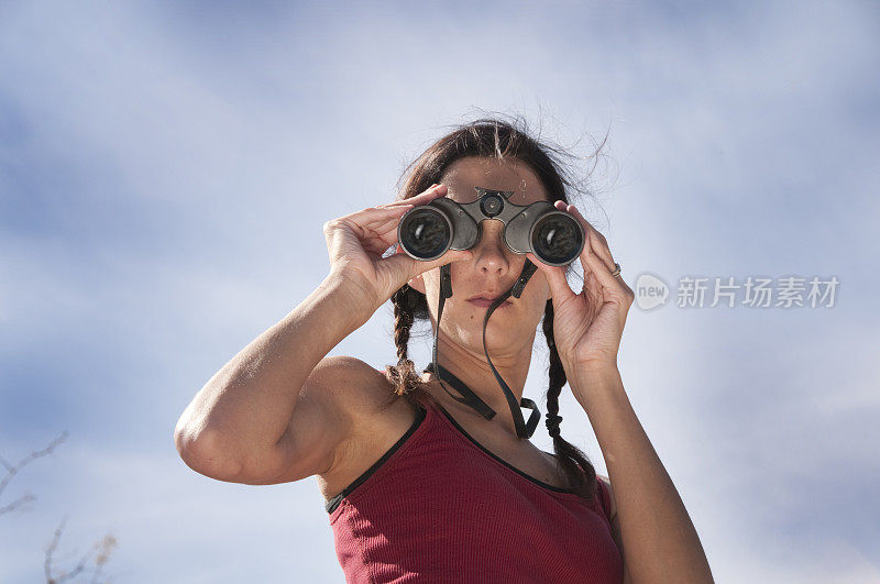 女人用双筒望远镜直视着照相机