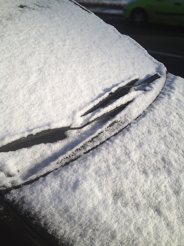阳光下融化的雪覆盖着汽车
