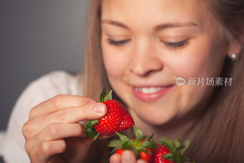 微笑的女孩拿着新鲜的红草莓