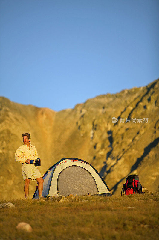 在帐篷和背包旁边的山上徒步旅行者