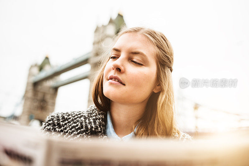 一个女人在塔桥下看报纸