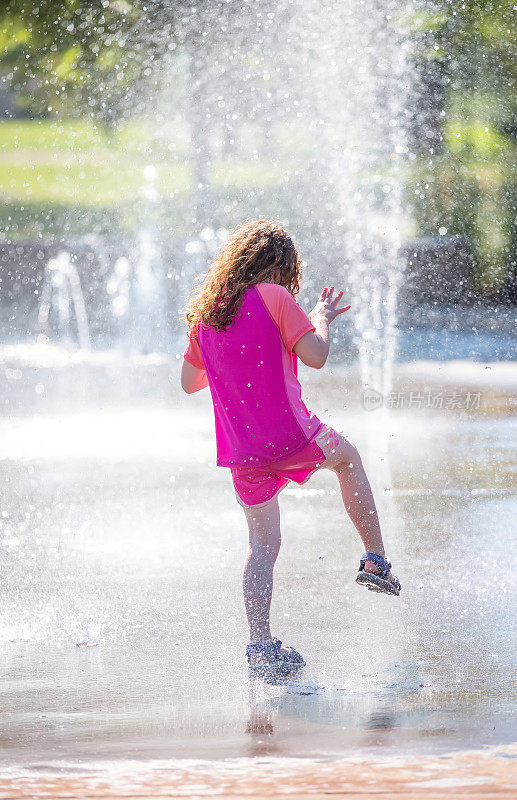 在户外水花公园喷泉里玩耍的女孩