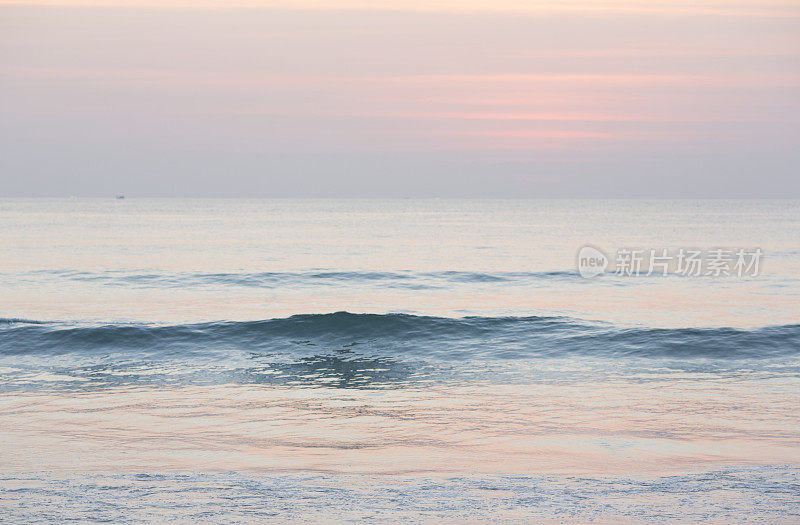 温柔的波浪翻滚过平静的海面，日出