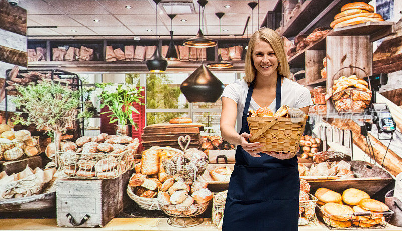 微笑的女面包师提着篮子在面包店
