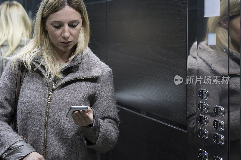 女商人在电梯里用智能手机