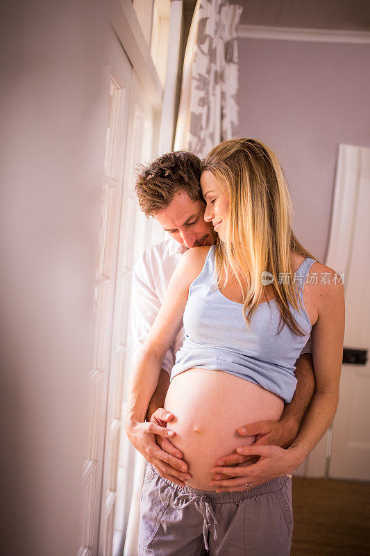 一对深情的夫妇抱着妻子怀孕的肚子