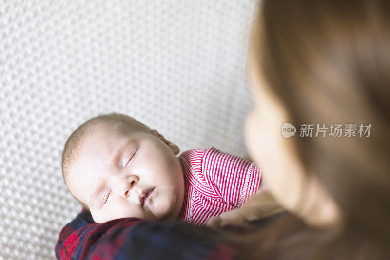 刚出生的婴儿睡在妈妈的怀里