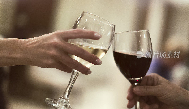 两名妇女一边庆祝好消息一边喝着红酒和白葡萄酒。