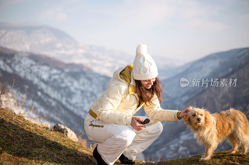 一个女人带着狗在雪地里走在村里的街道上