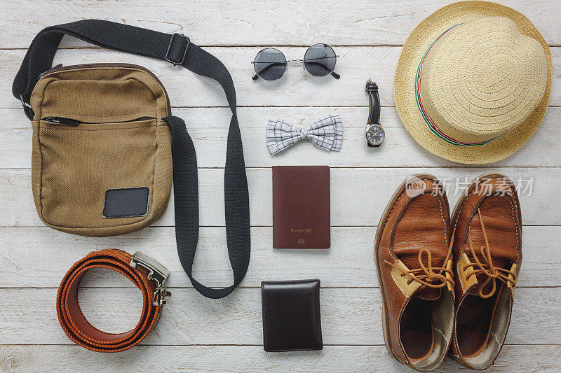 俯视图配件旅行与男装概念上的木材背景。男士物品领结、钱包、皮鞋、手表、太阳镜、手袋、帽子、腰带、护照等木质背景。白色的空白。