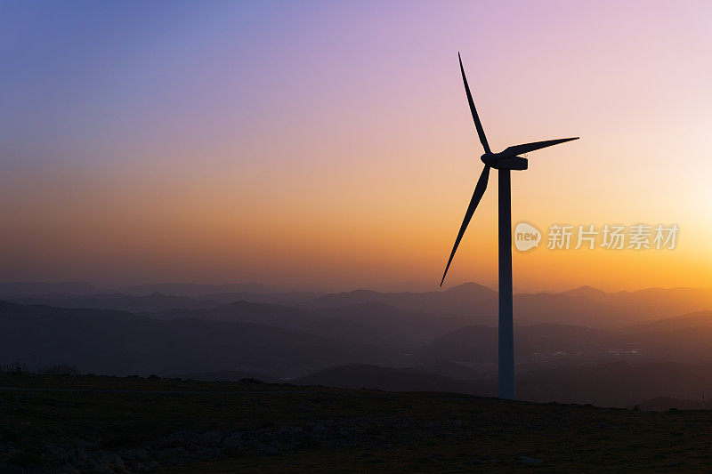 日落时山上风力涡轮机的剪影