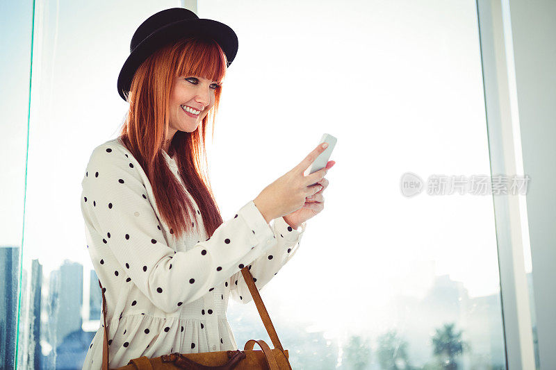 微笑的时髦女人用她的智能手机发短信