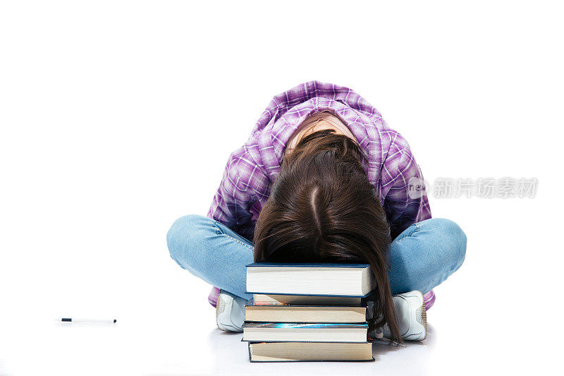 坐在地板上睡在书上的女人