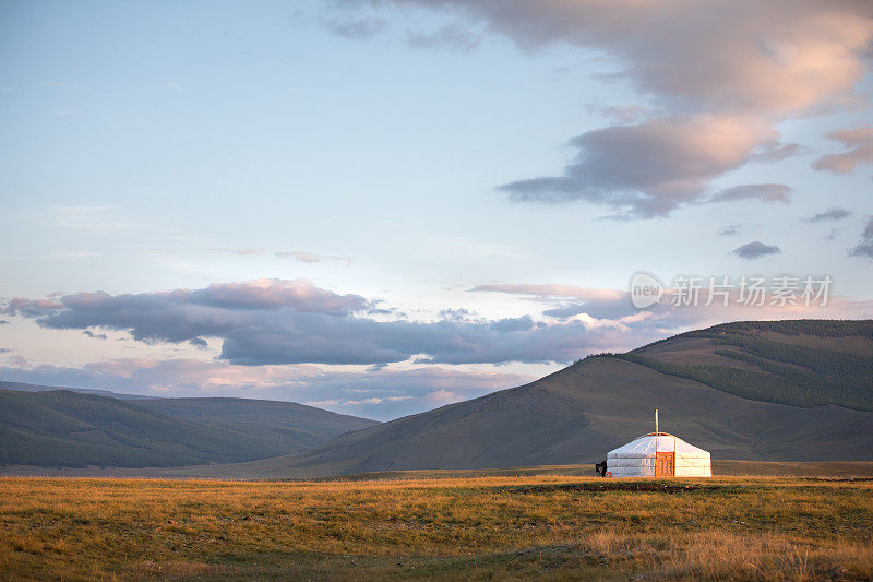 传统蒙古蒙古包在山的背景下日落的光。