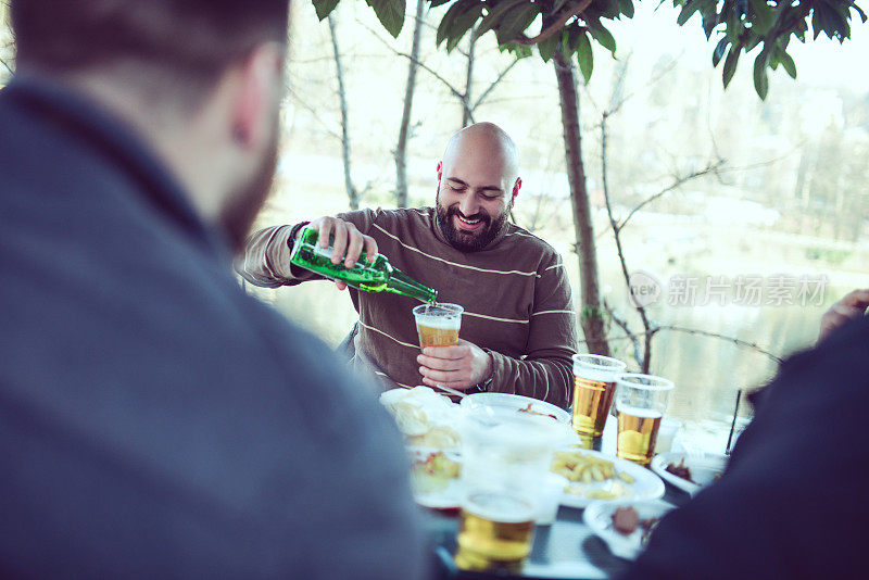 一群男性朋友喝啤酒，在外面野餐