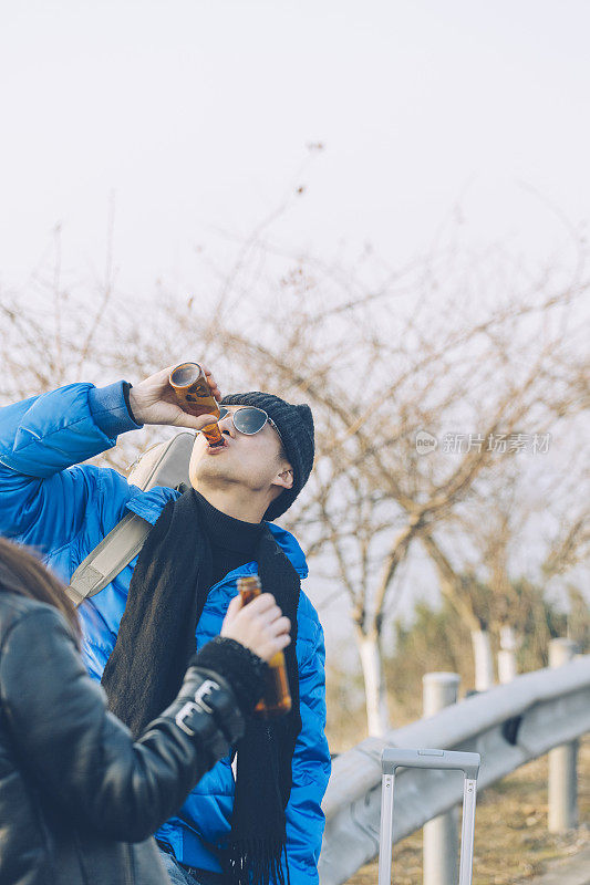 一对年轻多情的情侣对着天空喝啤酒