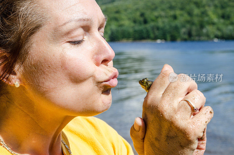 近距离的女人准备亲吻一个真正的青蛙在户外夏季假期