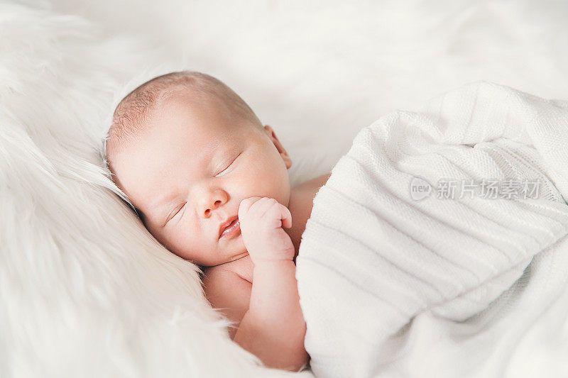 睡在白色毯子里的新生婴儿。