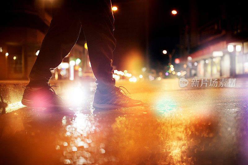 一个不认识的人在雨夜踏进水坑