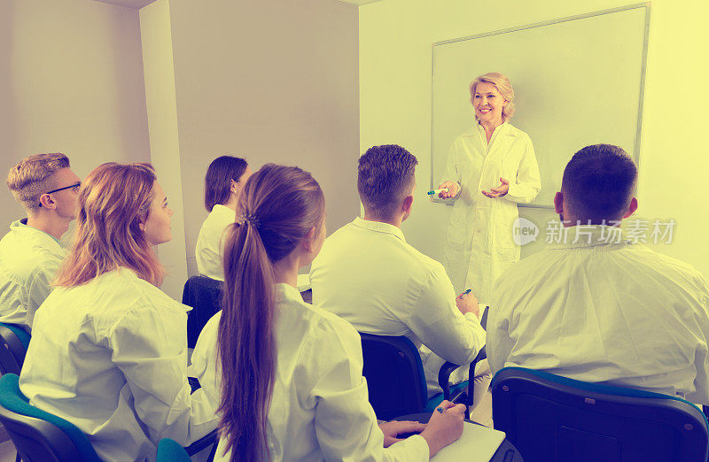一群医学生在课堂上专心听女老师讲课