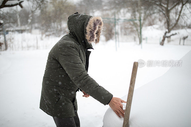 困在雪。老人用铁锹铲雪