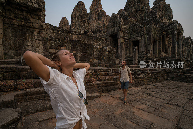 一对在亚洲旅游的游客，在夕阳下凝视美丽的古庙和古老的废墟;人发现探索理念