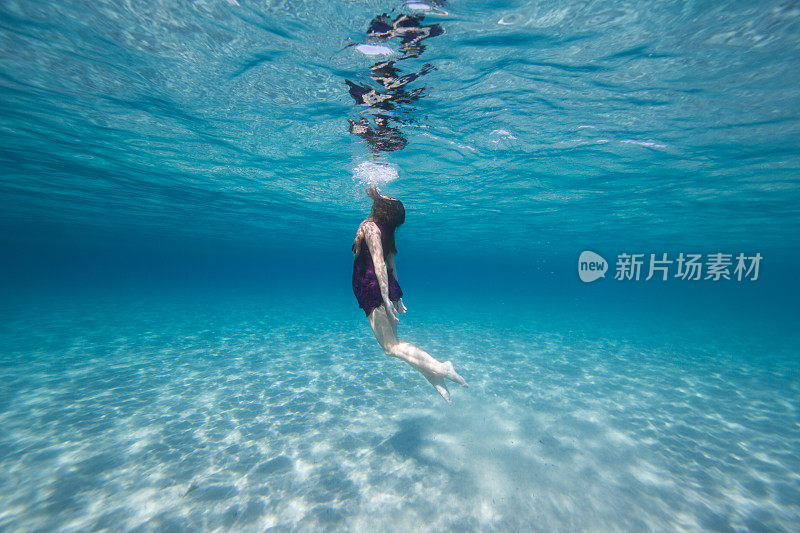 穿着紫色衣服的年轻女子在水里游泳