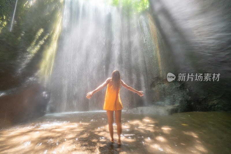 在巴厘岛的热带雨林中，旅行的年轻女子张开双臂拥抱大自然的美丽。人们以自然为旅游理念。