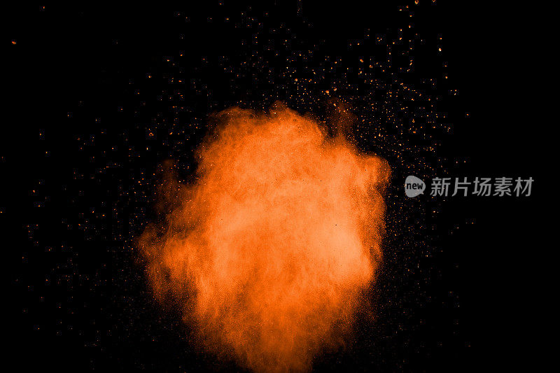 橙色尘埃粒子在黑色背景上爆炸。彩色粉末粉尘飞溅。
