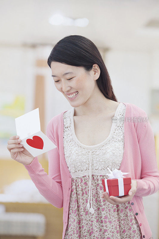 中国女人看情人节卡片，拿着礼物