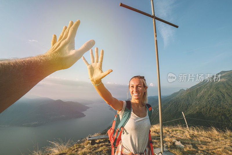 两个徒步旅行者在山顶击掌庆祝的个人视角