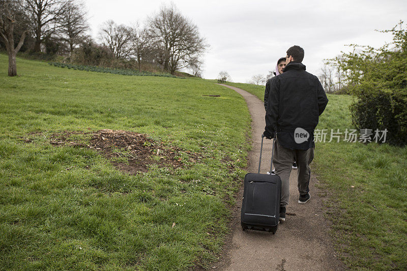 提着行李箱在布里斯托尔的布兰登山公园散步的年轻男人