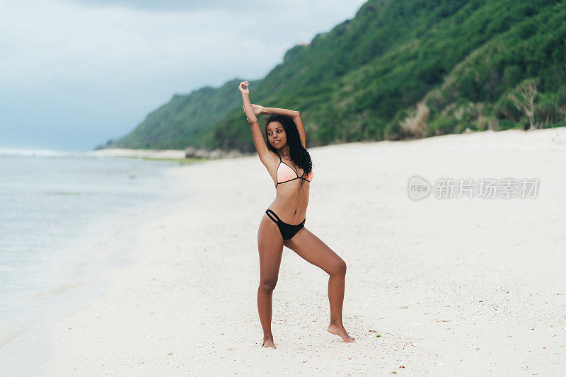 苗条性感的黑皮肤的女孩在泳装摆姿势在沙滩上的沙子。美国黑人妇女在天堂岛休息