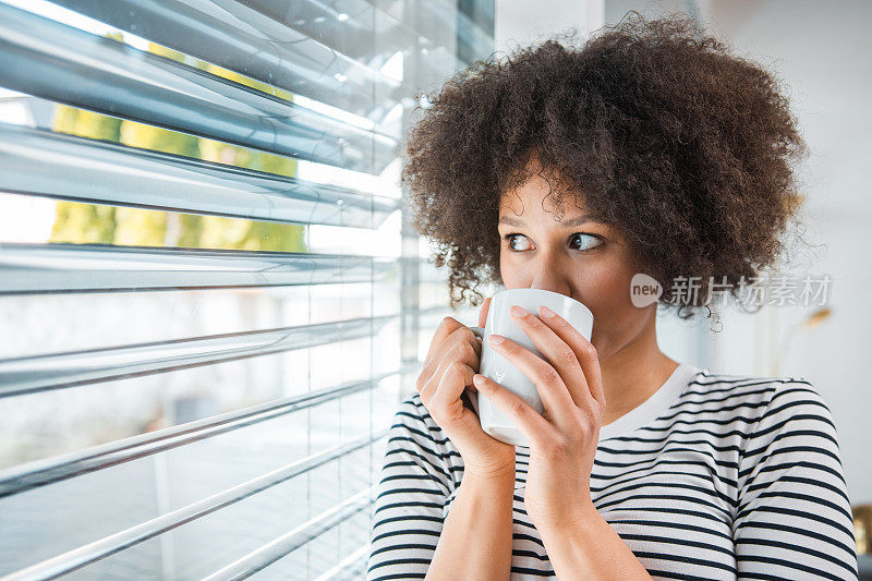 非裔美国妇女早上在窗边喝茶