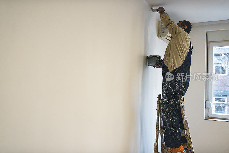 房屋油漆工正在用油漆刷刷白墙
